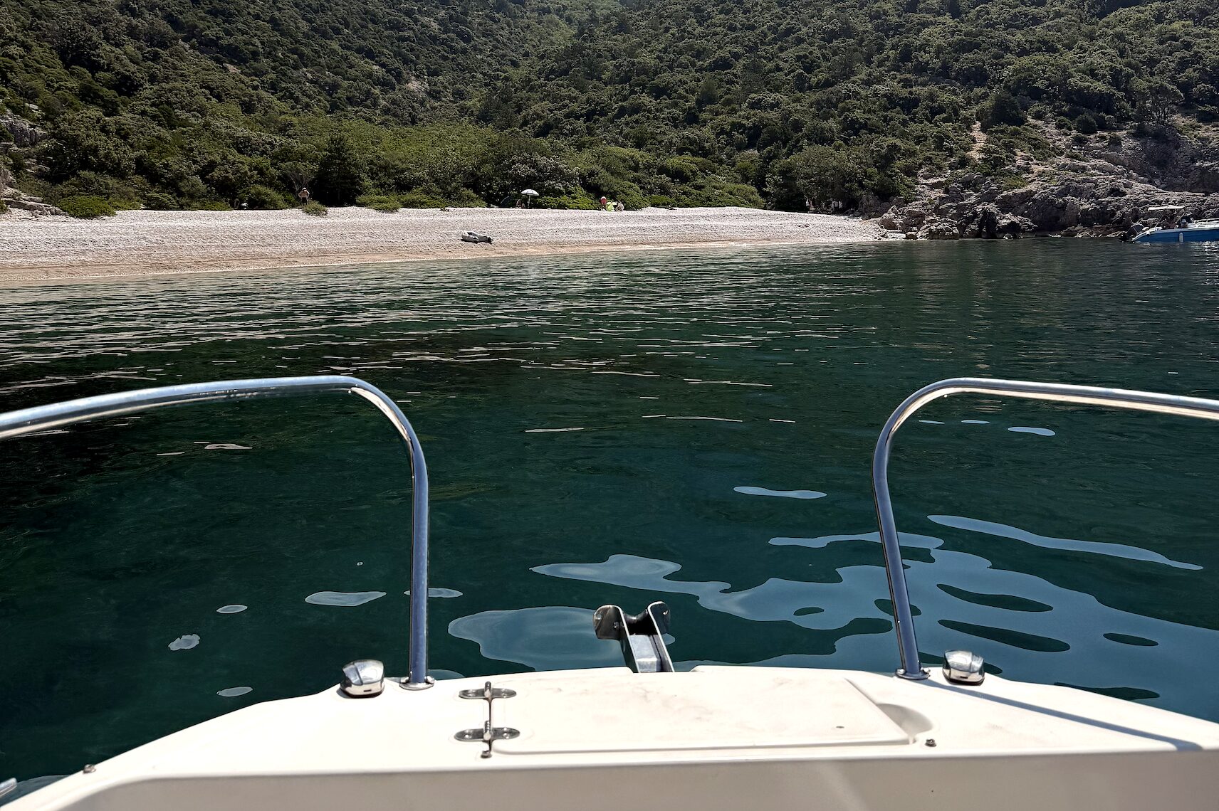 A secluded cove on the eastern Istrian coast A forested pebble cove seen from the bow of a small boat