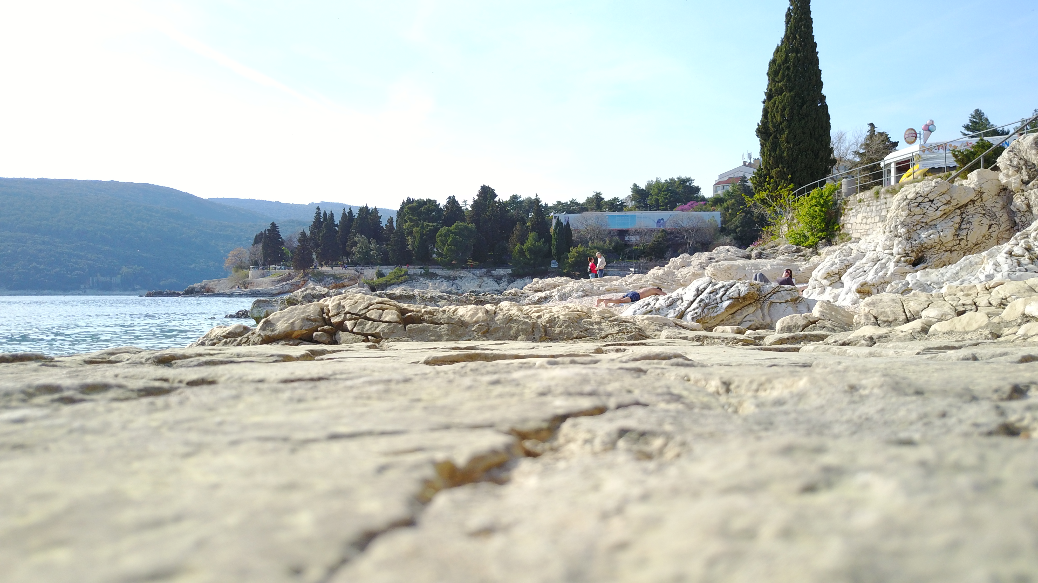 Jesensko sunce na istočnoj obali Istre Posjetitelji odmaraju na osunčanim stijenama iznad bistrog mora kraj Rapca u jesen