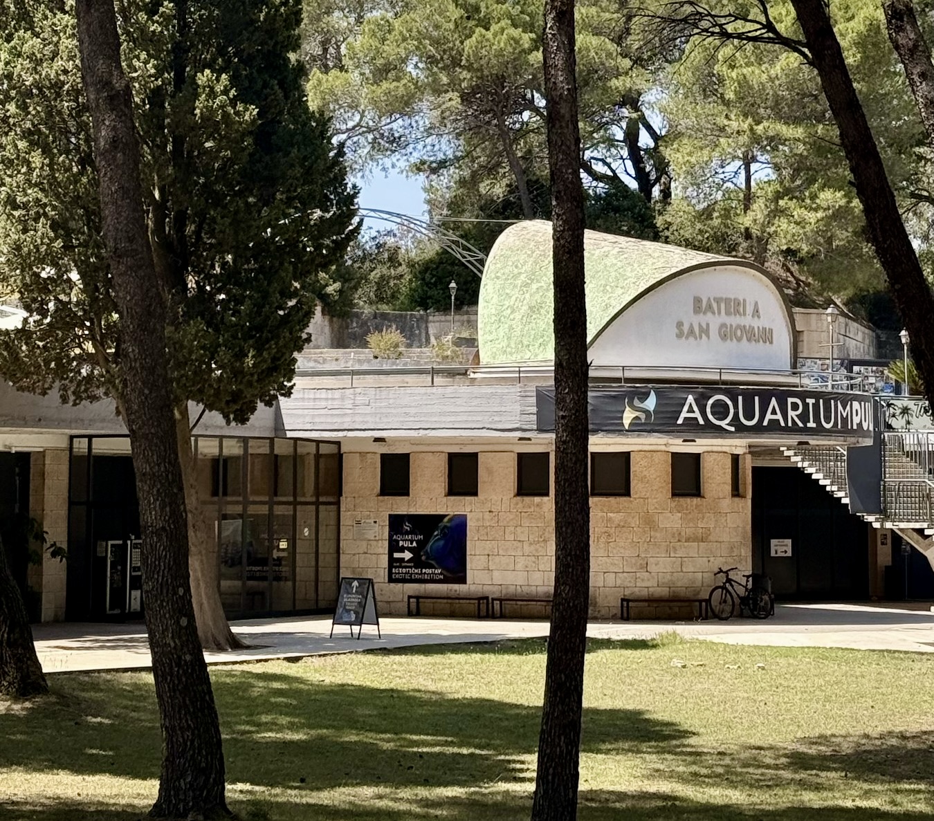 The public entrance to Aquarium Pula Battery San Giovanni entrance to Aquarium Pula beneath pine trees